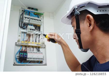 Electrician working checking a switchboard with fuses Electrician working checking a switchboard with fuses 128218855