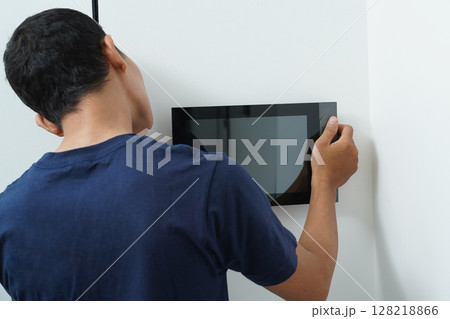 Worker with tablet computer checking alarm system 128218866