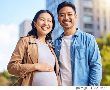 アジア人の若い妊婦と夫が笑顔で高層マンションの前でポーズ 128219432