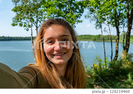 A Smiling Woman Posing Gracefully by the Serene Lake in the Heart of Natures Beauty A Smiling Woman Posing Gracefully by the Serene Lake in the Heart of Natures Beauty 128219460