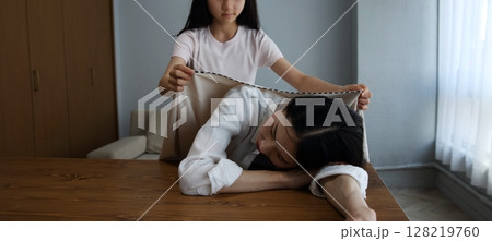 疲れて寝てしまった母親に毛布をかけてあげる娘のイメージ 128219760