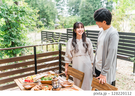 ウッドデッキ・テラス席・バルコニー席で食事するカップル・夫婦(グランピング・ベランピング) ウッドデッキ・テラス席・バルコニー席で食事するカップル・夫婦(グランピング・ベランピング) 128220112