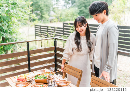 ウッドデッキ・テラス席・バルコニー席で食事するカップル・夫婦(グランピング・ベランピング) ウッドデッキ・テラス席・バルコニー席で食事するカップル・夫婦(グランピング・ベランピング) 128220113