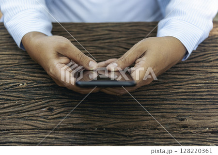 Close up woman hands using smartphone online video call texting message. Female hand touch empty screen cellphone smart tablet on hands using mobile app home office. Asian woman sitting wooden table Close up woman hands using smartphone online video call texting message. Female hand touch empty screen cellphone smart tablet on hands using mobile app home office. Asian woman sitting wooden table 128220361