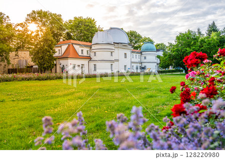Enjoy a serene view of the Stefanik Observatory on Petrin hill in Prague as the sun sets, surrounded by lush greenery and colorful flowers in bloom. Enjoy a serene view of the Stefanik Observatory on Petrin hill in Prague as the sun sets, surrounded by lush greenery and colorful flowers in bloom. 128220980