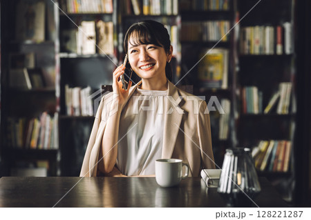 書斎,図書館で通話,電話しながらタブレットPCを使うアジア人女性,ビジネスウーマン 書斎,図書館で通話,電話しながらタブレットPCを使うアジア人女性,ビジネスウーマン 128221287