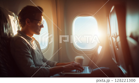 飛行機の窓辺でタイピングする男性の静かな旅のシーン 128221300