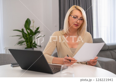 Blonde professional psychologist taking notes and uses laptop. 128221941