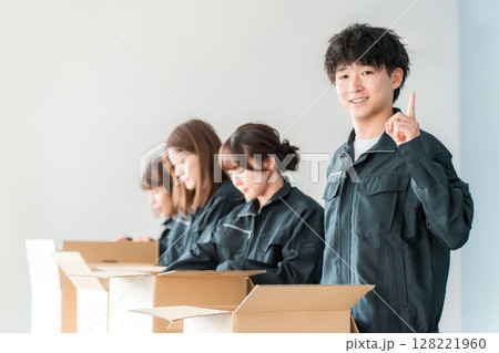 ダンボールに梱包作業をする運送・物流・宅急便・宅配便・流通・配達・倉庫・宅配業者の作業員の男女 ダンボールに梱包作業をする運送・物流・宅急便・宅配便・流通・配達・倉庫・宅配業者の作業員の男女 128221960