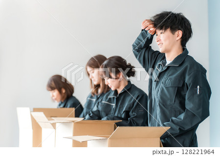 ダンボールに梱包作業をする運送・物流・宅急便・宅配便・流通・配達・倉庫・宅配業者の作業員の男女 128221964