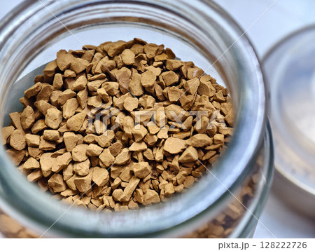 Close-up of instant coffee granules in a glass jar aromatic, textured, and rich brown tones. Close-up of instant coffee granules in a glass jar aromatic, textured, and rich brown tones. 128222726