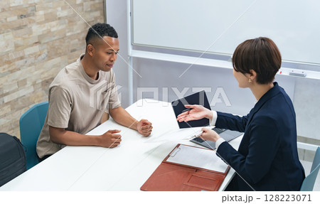面談する黒人男性と日本人女性スタッフ 128223071