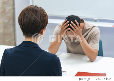 悩む黒人男性と面談する日本人女性スタッフ 128223102