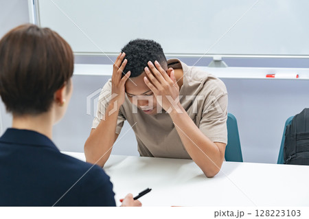 悩む黒人男性と面談する日本人女性スタッフ 128223103