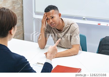 悩む黒人男性と面談する日本人女性スタッフ 悩む黒人男性と面談する日本人女性スタッフ 128223108