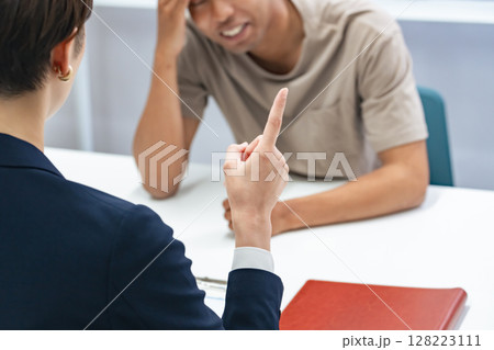 悩む黒人男性と面談する日本人女性スタッフ 128223111