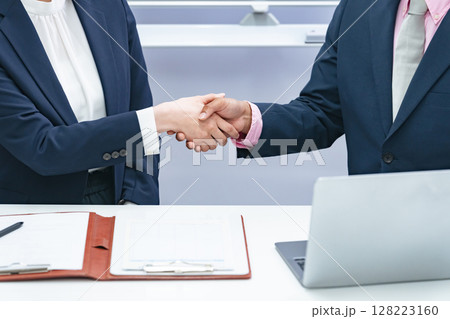 握手する黒人男性ビジネスマンと日本人女性スタッフ 握手する黒人男性ビジネスマンと日本人女性スタッフ 128223160