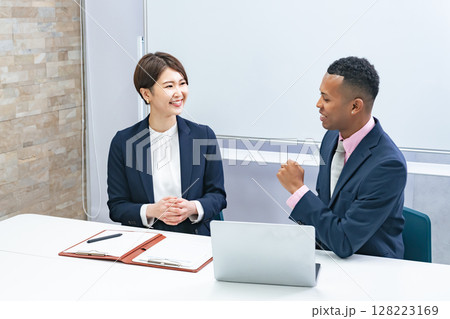 黒人男性ビジネスマンと面談する日本人女性スタッフ 黒人男性ビジネスマンと面談する日本人女性スタッフ 128223169