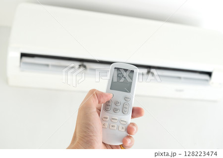 Man's hand using remote control open The air conditioner is cooled to 25 degrees Celsius in his bedroom. Health concepts and energy savings Man's hand using remote control open The air conditioner is cooled to 25 degrees Celsius in his bedroom. Health concepts and energy savings 128223474