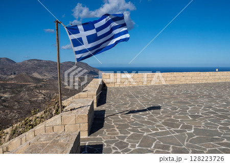 Greek flag waving on a viewpoint overlooking mountains and sea in crete, greece Greek flag waving on a viewpoint overlooking mountains and sea in crete, greece 128223726