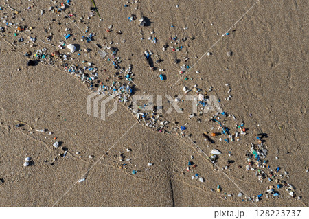 Microplastics polluting sand on the beach, environmental disaster 128223737