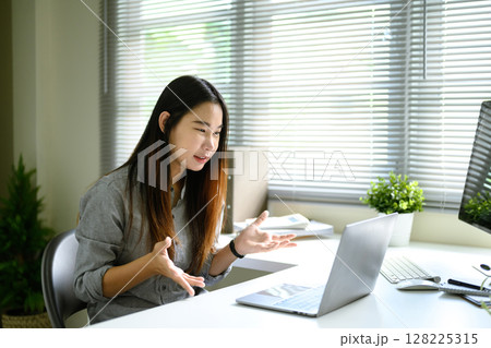 Female accountant in video call discussing financial data at a desk with laptop and documents Female accountant in video call discussing financial data at a desk with laptop and documents 128225315