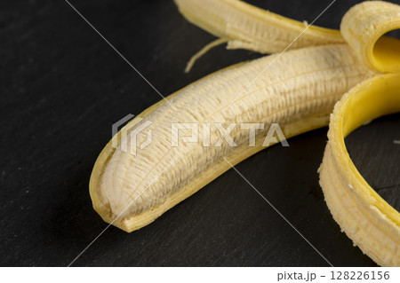 open ripe yellow banana on a black slate board, ripe and sweet yellow banana on a kitchen board made of black stone open ripe yellow banana on a black slate board, ripe and sweet yellow banana on a kitchen board made of black stone 128226156