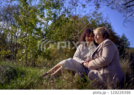 a   middle-aged daughter and elderly mother together on a walk in the autumn forest 128226386