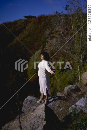 middle-aged woman free on the rocks above the precipice in autumn 128226390