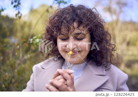 middle-aged woman with dark curly hair in light beige suit and coat enjoying nature in autumn forest 128226425