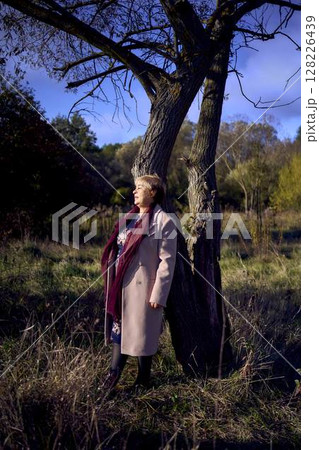 elderly woman with gray hair in light beige coat enjoying nature in autumn forest elderly woman with gray hair in light beige coat enjoying nature in autumn forest 128226439