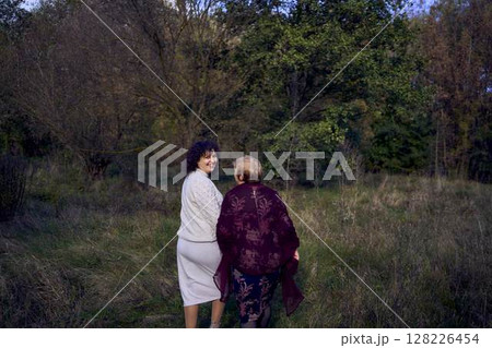 middle-aged daughter and elderly mother together on a walk in the autumn forest 128226454