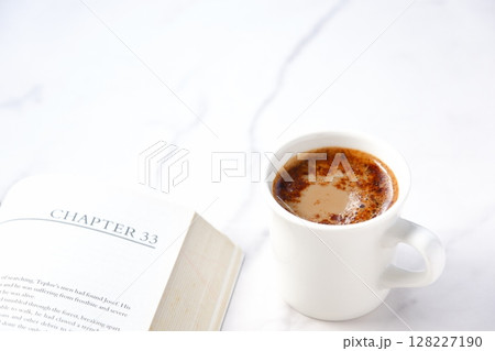 ペーパーバック（洋書）とコーヒーの入ったコーヒーカップで、コーヒーを飲みながら読書中のイメージ 128227190
