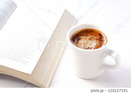 ペーパーバック（洋書）とコーヒーの入ったコーヒーカップで、コーヒーを飲みながら読書中のイメージ 128227191