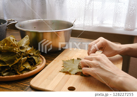 Preparation of dolma using grape leaves and fresh ingredients in a cozy kitchen setting 128227255