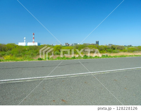 土手のサイクリング道路から見る春の江戸川河川敷と対岸の建物風景 土手のサイクリング道路から見る春の江戸川河川敷と対岸の建物風景 128228126