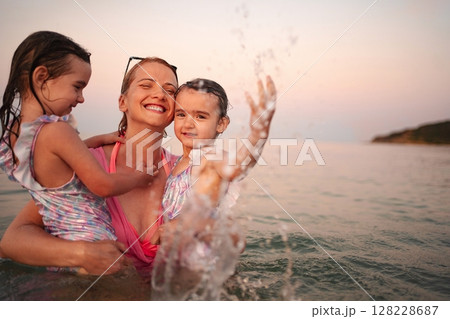 Joyful family playing in the water at a beautiful beach sunset 128228687