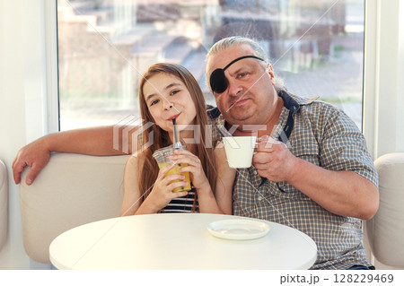 Father and daughter enjoying drinks at a cozy cafe together 128229469