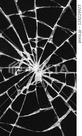 Abstract close-up of shattered glass on a black background illustrating patterns and textures created by breaks and cracks Abstract close-up of shattered glass on a black background illustrating patterns and textures created by breaks and cracks 128229923