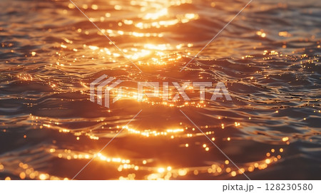 Golden sunlight reflecting on calm rippling water surface at sunset 128230580