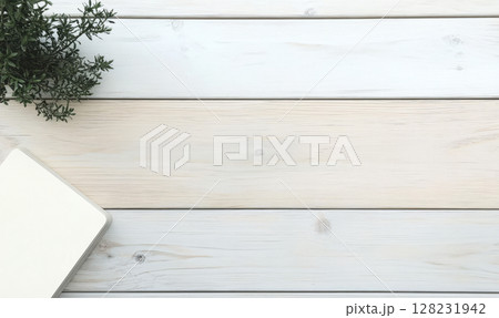 Simple workspace setup with notepad and greenery on light wooden table 128231942
