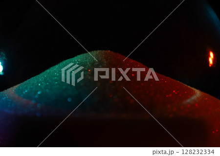 Rainbow sparkly hourglass sand on dark background. Minimalist low key poto for concepts of time, travel to the desert 128232334
