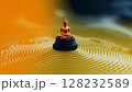 Golden Buddha figurine surrounded by concentric ripples in tranquil water at a serene location 128232589