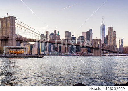 A panoramic sunset view of the Brooklyn Bridge stretching towards Manhattan 128232669