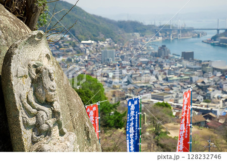 尾道・千光寺の石仏と眼下に広がる春の街並み、尾道水道を望む情緒豊かな風景 尾道・千光寺の石仏と眼下に広がる春の街並み、尾道水道を望む情緒豊かな風景 128232746