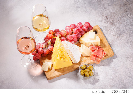 A delectable arrangement of various cheeses, fresh grapes, prosciutto and wine 128232840
