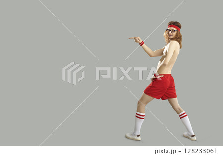 Funny shirtless thin man in sports shorts pointing with finger to advertising copy space Funny shirtless thin man in sports shorts pointing with finger to advertising copy space 128233061
