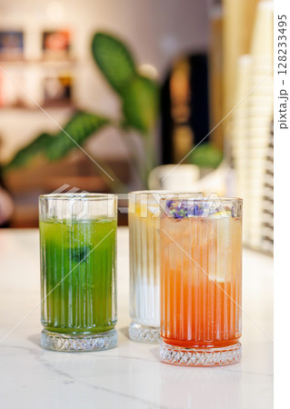 Assorted summer lemonades in glass jars with fresh fruits, ice, and garnishes 128233495