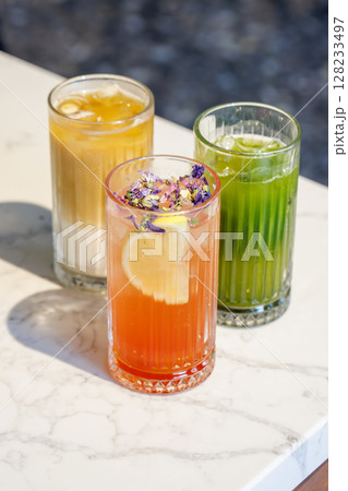 Assorted summer lemonades in glass jars with fresh fruits, ice, and garnishes 128233497