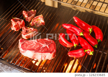 Juicy steaks and bell peppers sizzling on a grill Juicy steaks and bell peppers sizzling on a grill 128233685